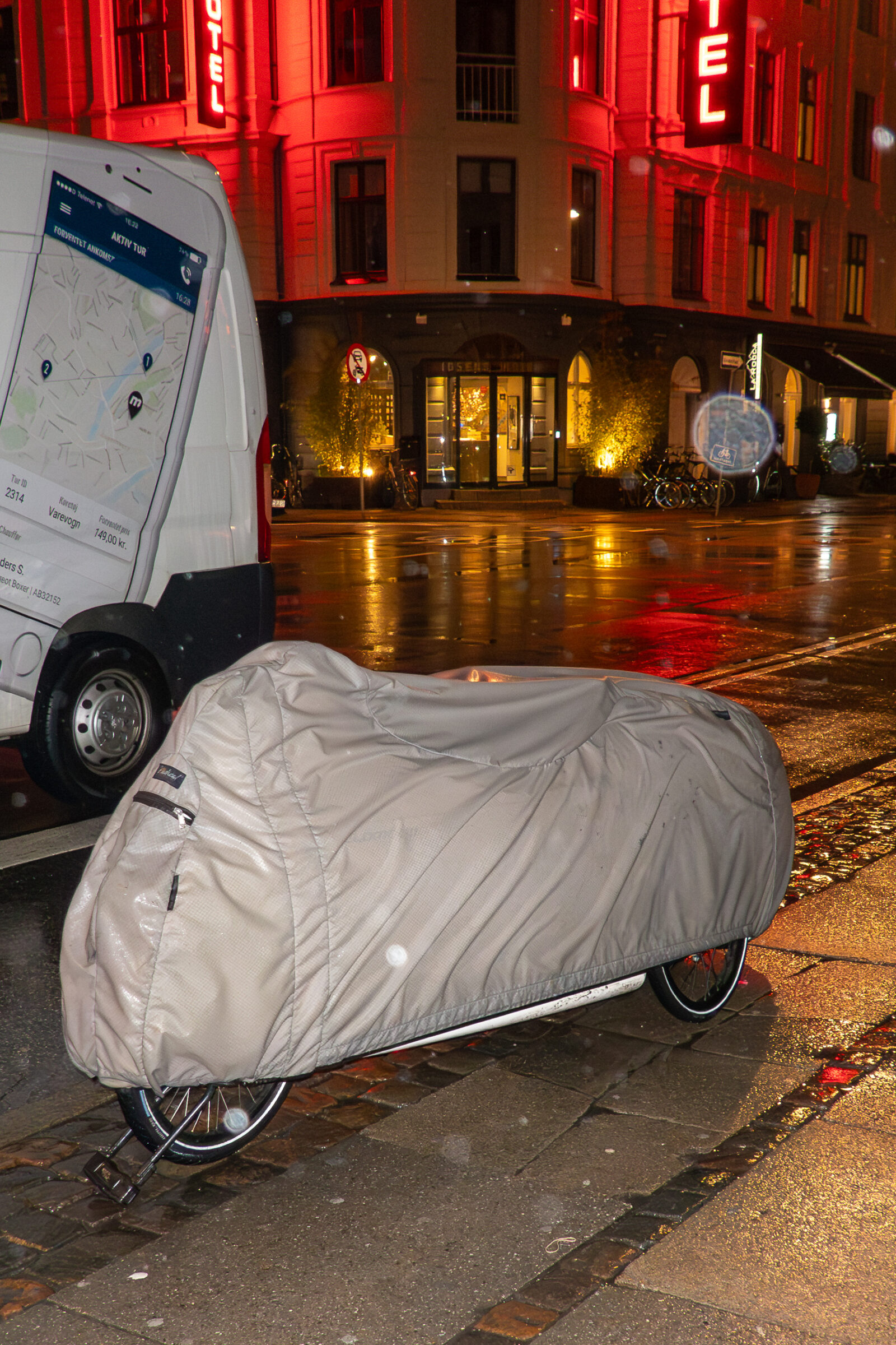 A recumbent tricycle in a raincoat, parked for the night.